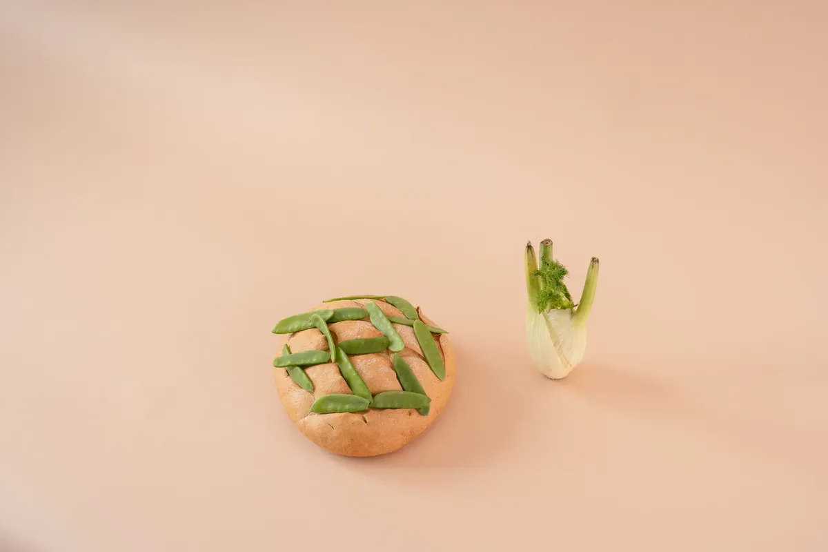 Creative display of bread with green peas and fennel on beige background.
