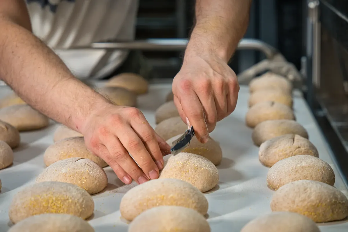 Hands shaping artisan bread in a Berlin bakery, showcasing craftsmanship and skill.