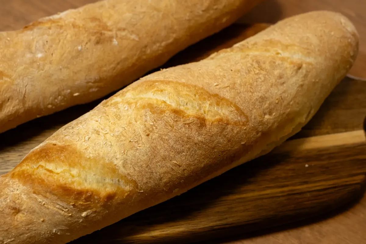 Crusty artisan baguettes resting on a wooden board, showcasing a classic French bread style.