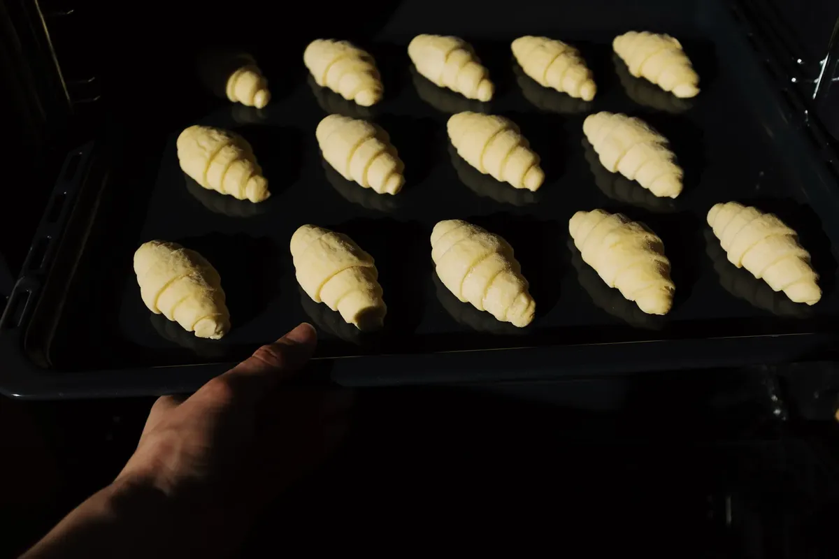 Golden croissant dough lined up on a baking tray, ready for the oven.