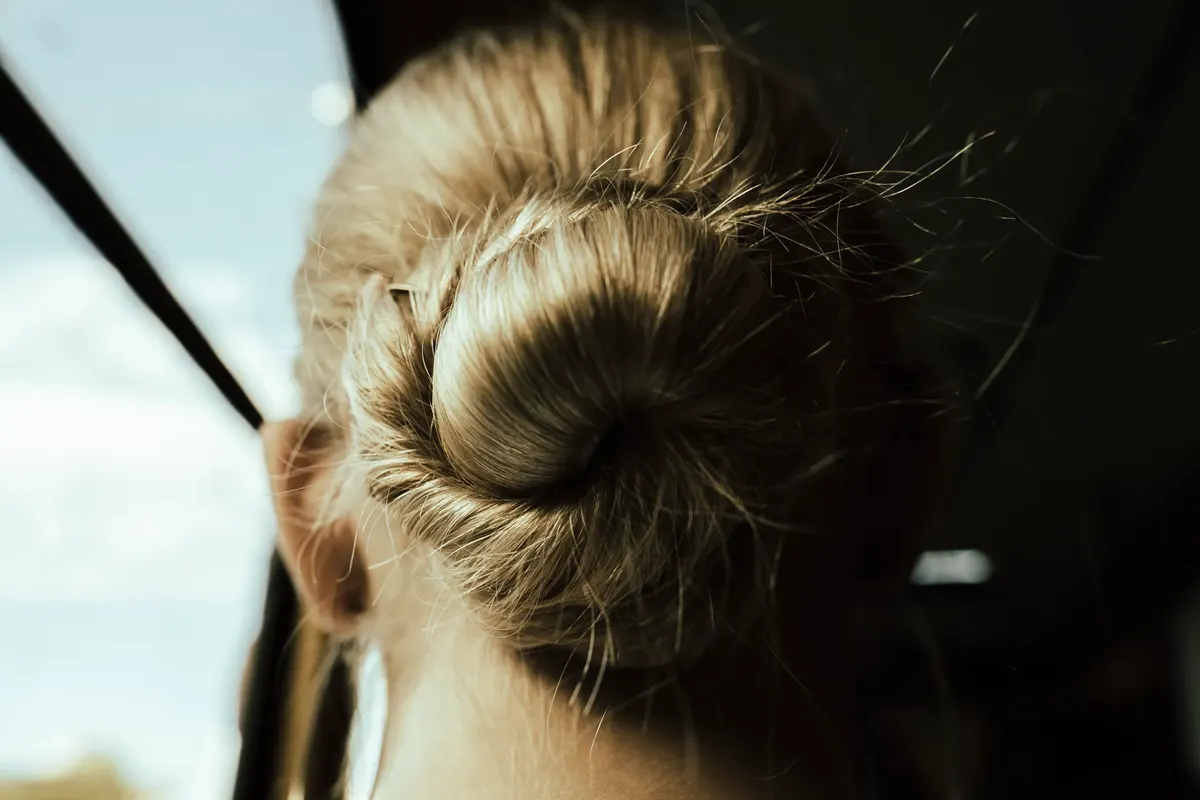 Close-up of a blonde hair bun illuminated by sunlight, showcasing elegant fashion.