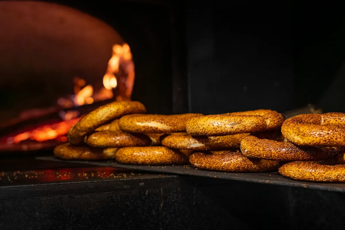 Golden bread rings baked in a traditional oven with visible flames creating a rustic ambiance.
