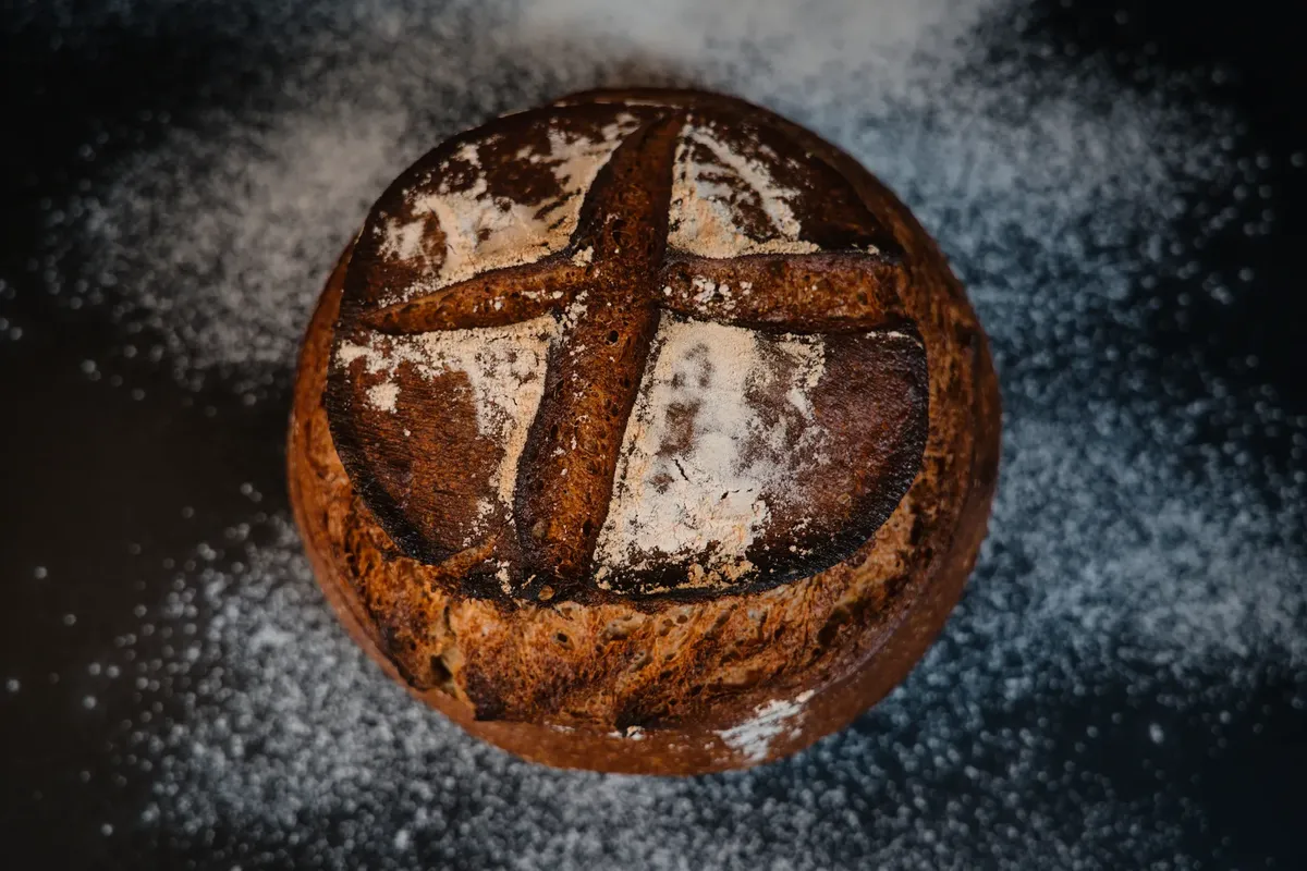 Freshly baked artisan bread with a rustic cross pattern, captured in a bakery setting.