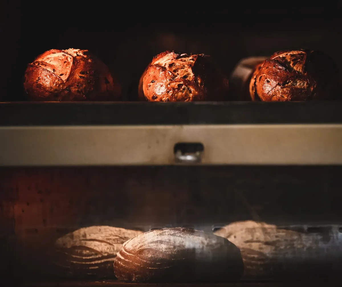 Freshly baked artisan bread inside a hot oven, showcasing the rustic texture and golden crust.