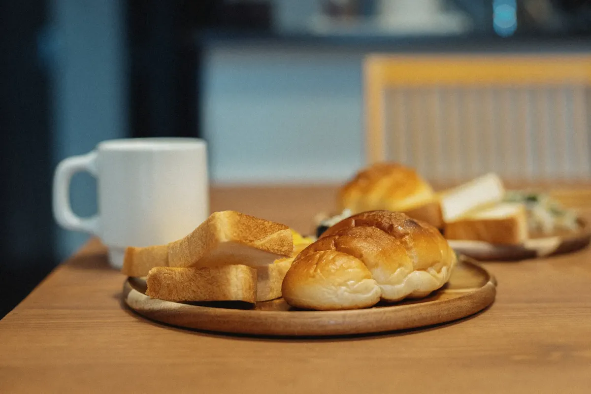 温かい朝のセットアップ：日本風のパンとコーヒーが木の台に置かれた。