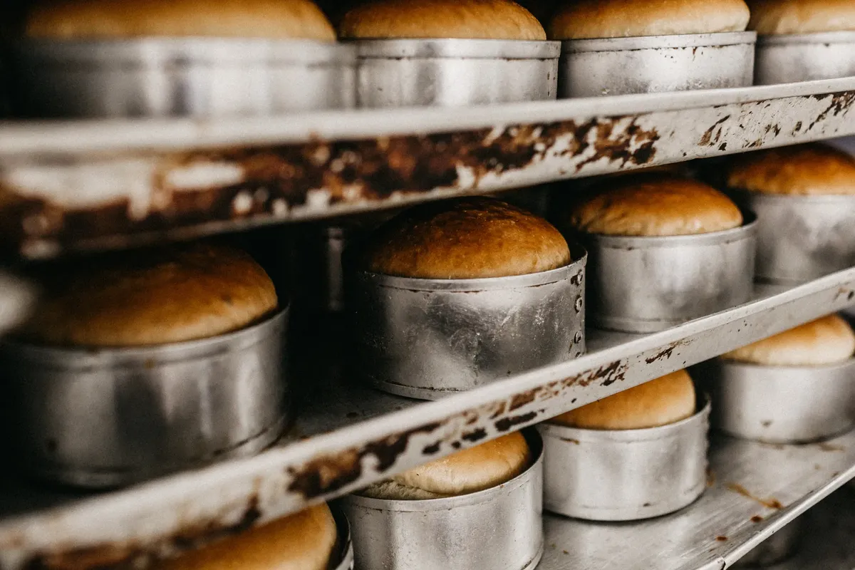 Close-up of freshly baked bread in metal bakeware on a bakery rack.