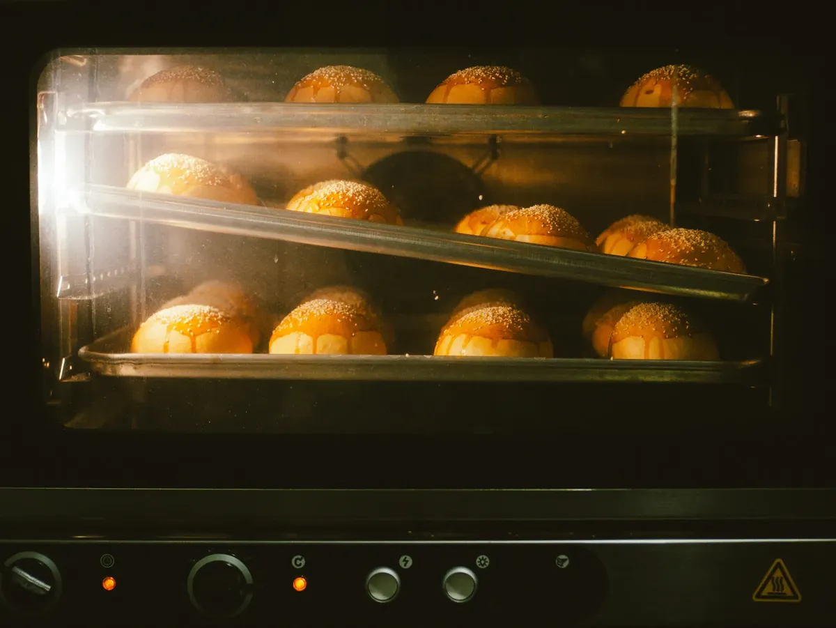 Golden brown bread rolls baking in an oven, showcasing warmth and homey ambience.