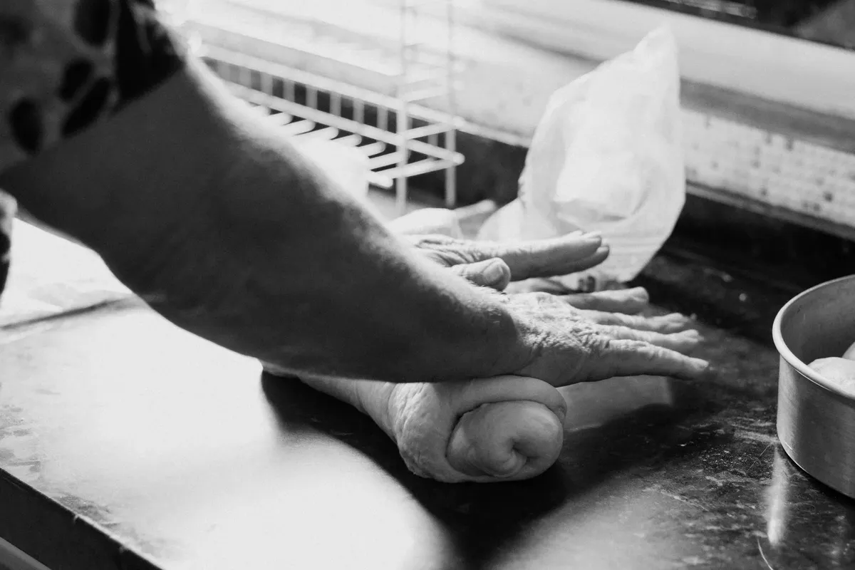 Black and white photo of hands kneading dough on a kitchen counter. Perfect for baking themes.